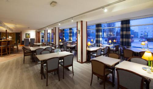 a restaurant with tables and chairs and a large window at Hotel Kauppi in Tampere