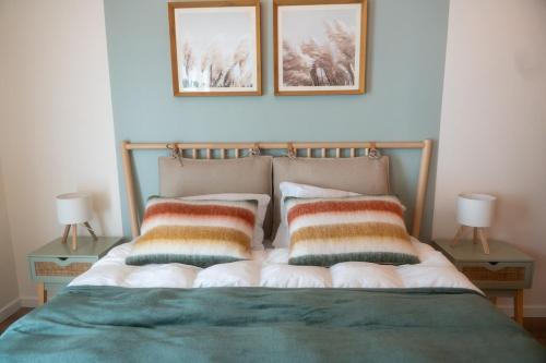 - un lit avec 2 oreillers et 2 photos sur le mur dans l'établissement Chez Edgard et Ernest, balcon et parking, à Saint-Valery-sur-Somme