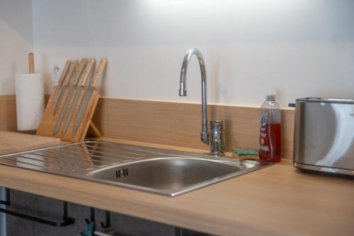 - un évier en acier inoxydable dans une cuisine avec un comptoir dans l'établissement Chez Edgard et Ernest, balcon et parking, à Saint-Valery-sur-Somme