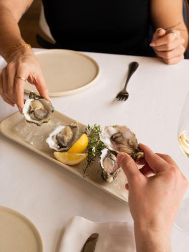a plate of oysters with lemon on a table at Hostal Empúries in L'Escala
