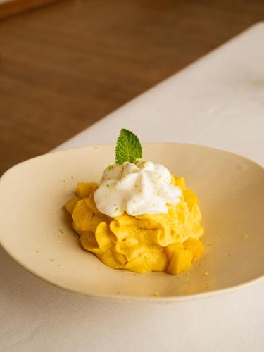 a dessert on a plate with whipped cream and a mint leaf at Hostal Empúries in L'Escala