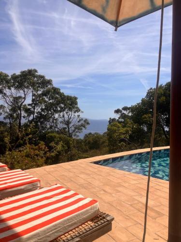 une piscine avec deux chaises longues et un parasol dans l'établissement Li Maiou Beautiful sea view property, very quiet, à Rayol-Canadel-sur-Mer