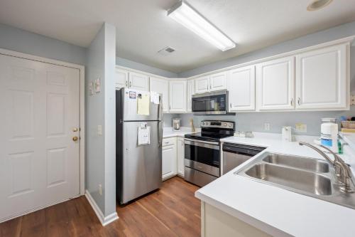 a kitchen with white cabinets and a stainless steel refrigerator at 53C Tee to Sea condo in Pawleys Island