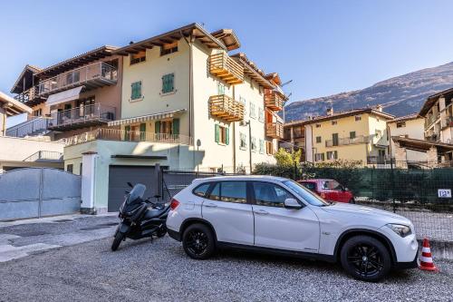 a white car and a motorcycle parked in front of a building at Appartamento La diMosa in Dro