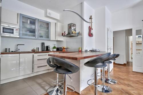 - une cuisine avec un comptoir avec des tabourets noirs dans l'établissement Family apartment with garden, à Paris