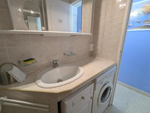 une salle de bain avec un lavabo et une machine à laver dans l'établissement Sol-y-Days Drakkar, Appartement familial 2 chambres avec parking, proche centre-ville et à 300m de la plage, au Grau-du-Roi