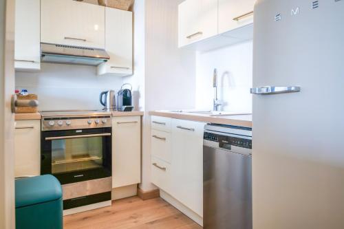 une cuisine avec des armoires blanches et des appareils en acier inoxydable dans l'établissement magnifique appartement terrasse - quartier presidents - 4 personnes, à Les Sables-dʼOlonne