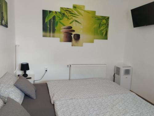 a bedroom with a bed and a painting on the wall at Viola Apartmanok Bogács in Bogács