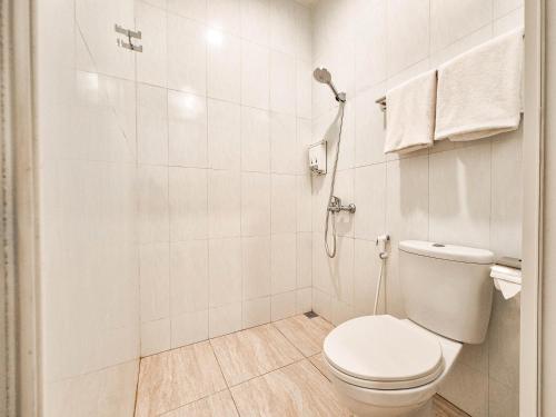 a white bathroom with a toilet and a shower at Pendhapa Art Space - PAS Limasan Homestay in Yogyakarta