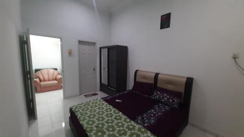 Glory Homestay Ipoh في ايبوه: غرفة نوم بها سرير وكرسي