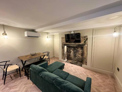 a living room with a green couch and a table at Akroyd House - The Wainhouse Room in Halifax