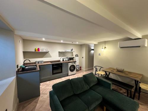 a living room with a green couch and a kitchen at Akroyd House - The Wainhouse Room in Halifax