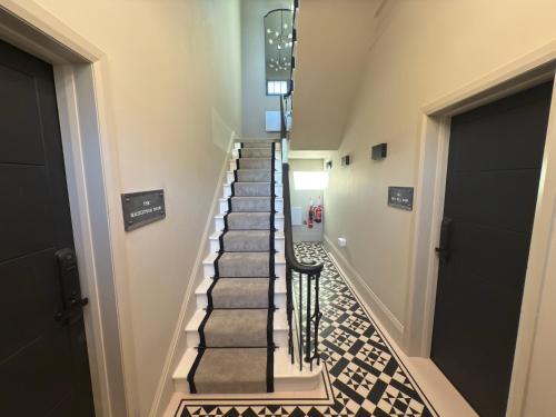 a hallway with a staircase with black and white tiles at Akroyd House - The Wainhouse Room in Halifax