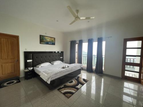 a bedroom with a bed and a ceiling fan at The Village Lodge Dalhousie in Banikhet