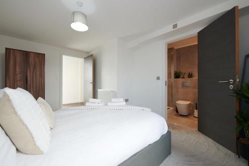 a white bedroom with a white bed and a bathroom at Luxury York Minster Penthouse - Free Gym & Parking in York