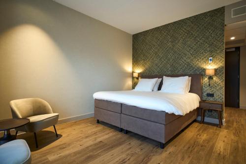 a hotel room with a bed and a chair at Eilandhotel Texel - Nieuw geopend hotel in De Cocksdorp