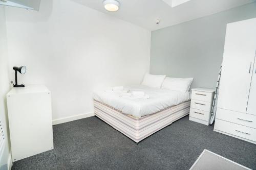 a white bedroom with a bed and a dresser at Compact & Cosy Central Coventry Budget Studio in Coventry