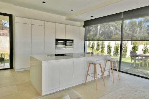 een keuken met witte kasten en een aanrecht met krukken bij Villa Clara chambre double in La Ciotat