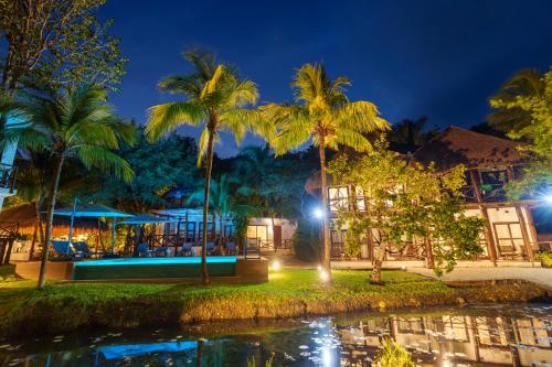 a resort with a pool and palm trees at night at Azulea Bacalar Hotel & Spa - Lagoon Front in Bacalar