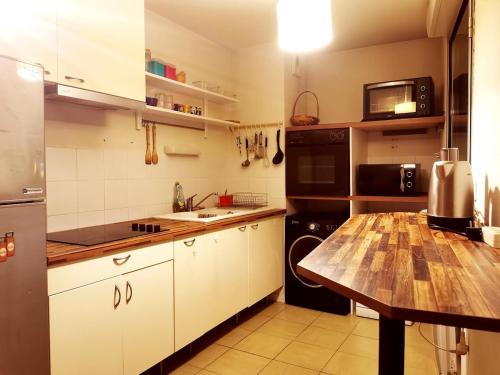 une cuisine avec des armoires blanches et une table en bois dans l'établissement Pleasant entire apartement in Bordeaux with parking, à Bordeaux