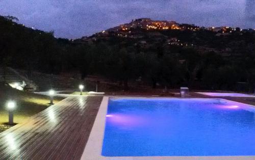una piscina por la noche con una montaña en el fondo en La Gabbianella e il Gatto en Castellabate