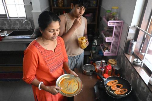 a woman standing in a kitchen preparing food at Ananda Holiday Home in Ambalavayal