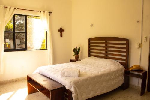 a bedroom with a large bed and a cross on the wall at El Prado- Rancho familiar en Yucatán in Xocchel
