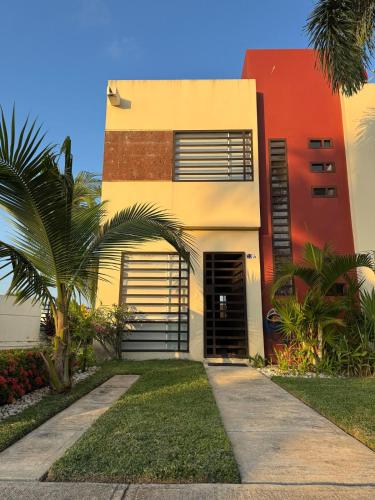 a house with a palm tree in front of it at Casa Mar y Laguna PUERTA AL SOL in General Juan N Alvarez International Airport