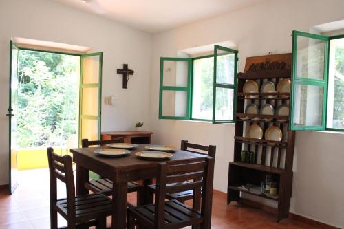 a dining room with a table and chairs and a cross on the wall at El Prado- Rancho familiar en Yucatán in Xocchel