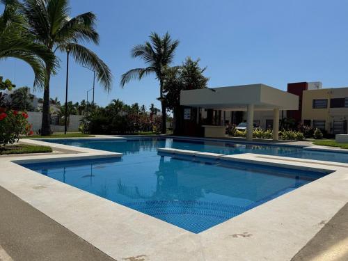 a swimming pool with blue water and palm trees at Casa Mar y Laguna PUERTA AL SOL in General Juan N Alvarez International Airport