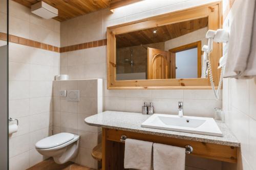 a bathroom with a sink and a toilet and a mirror at Garni Hotel Berc in Bled