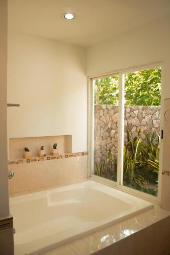 a white bath tub in a bathroom with a window at El Prado- Rancho familiar en Yucatán in Xocchel