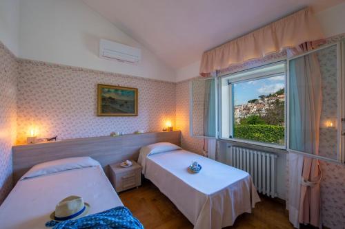 una camera d'albergo con due letti e una finestra di Il Piliero, a life of love a Cava deʼ Tirreni