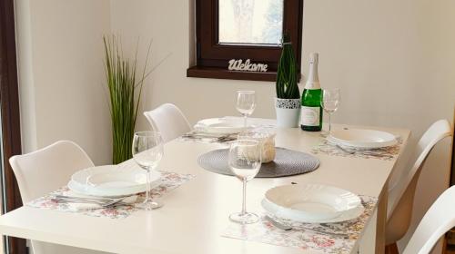 a white table with white plates and wine glasses at Palatinus Apartman Esztergom in Esztergom