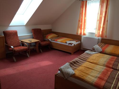 sypialnia z 2 łóżkami i krzesłami oraz oknem w obiekcie Penzion Rakovec w mieście Bukovinka