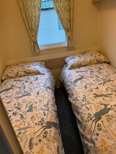 two beds in a small room with a window at Karen's Caravan in Great Yarmouth