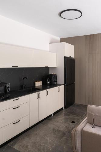 a kitchen with white cabinets and a black refrigerator at אחוזת בר אילן עם גקוזי יש בדירה ממד in Qiryat Motzkin