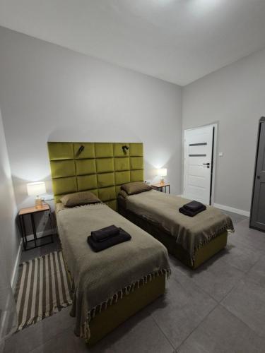 a bedroom with two beds and a yellow headboard at APARTAMENTY PRUCHNICKA in Jarosław