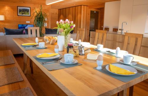 a large wooden table with plates and utensils on it at Ferienwohnung Naturnah in Dalaas