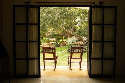 an open door with two chairs in a yard at El Prado- Rancho familiar en Yucatán in Xocchel
