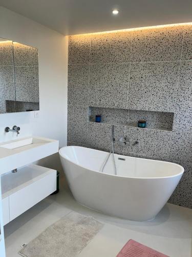 La salle de bains est pourvue d'une grande baignoire blanche et d'un lavabo. dans l'établissement Grande Villa avec Piscine, Pétanque et Vue Mer pour 12 Personnes, au Beausset