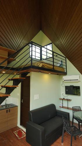 a living room with a couch and a spiral staircase at Private Hut in Thusharagiri in Vallikavungal