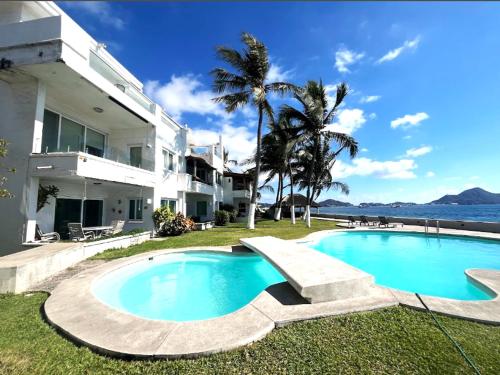 a house with a swimming pool in front of the ocean at Penthouse en Manzanillo a Pie de Playa in Manzanillo