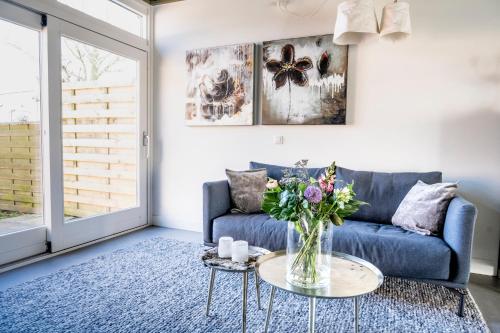 a living room with a blue couch and a table with flowers at Dyk hûs in Moddergat