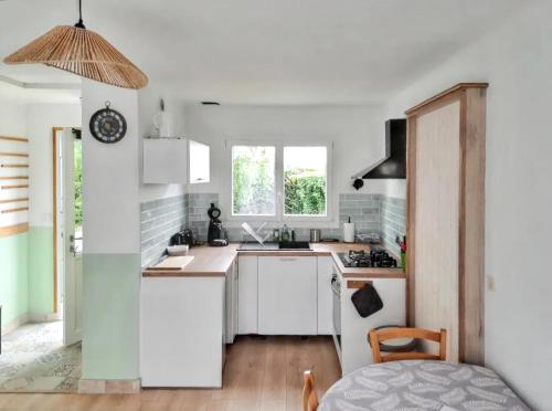 Elle comprend une petite cuisine avec des placards blancs et une fenêtre. dans l'établissement Maison familiale à proximité du Mont St Michel, à Saint-Méloir-des-Ondes