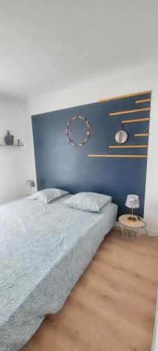 une chambre avec un lit et un mur bleu dans l'établissement Maison familiale à proximité du Mont St Michel, à Saint-Méloir-des-Ondes