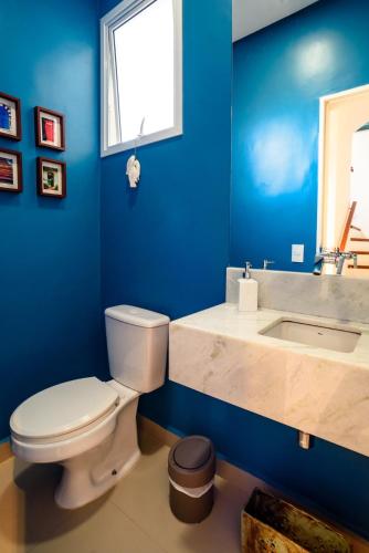 a blue bathroom with a toilet and a sink at Linda Casa de alto padrão em praia de Juquehy in São Sebastião