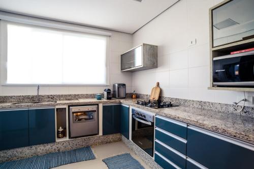 a kitchen with blue cabinets and a stove top oven at Linda Casa de alto padrão em praia de Juquehy in São Sebastião