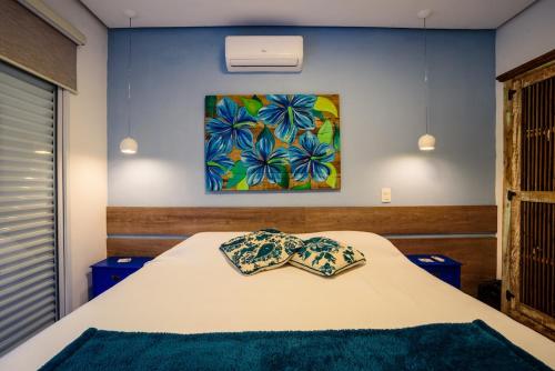 a bedroom with a bed and a painting on the wall at Linda Casa de alto padrão em praia de Juquehy in São Sebastião