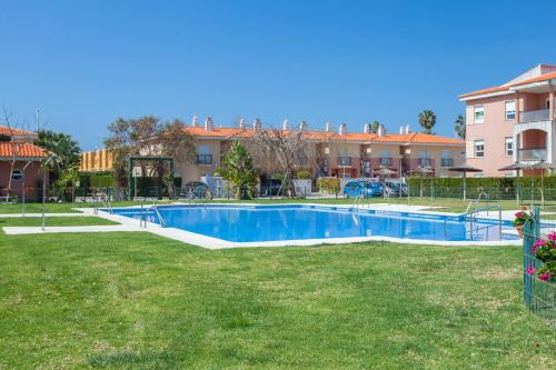 a swimming pool in a yard in front of a building at Divi Apartments Costa Ballena in Costa Ballena